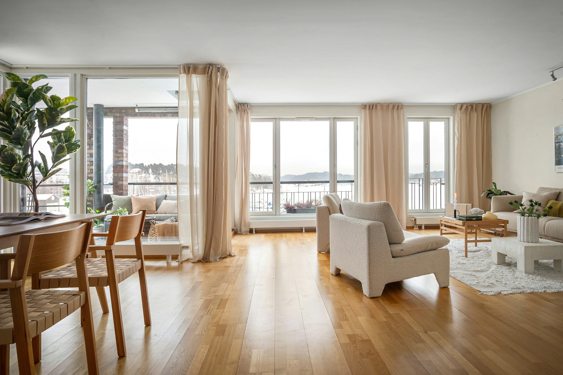 Bright modern living room with oak floors, neutral furniture, and large windows